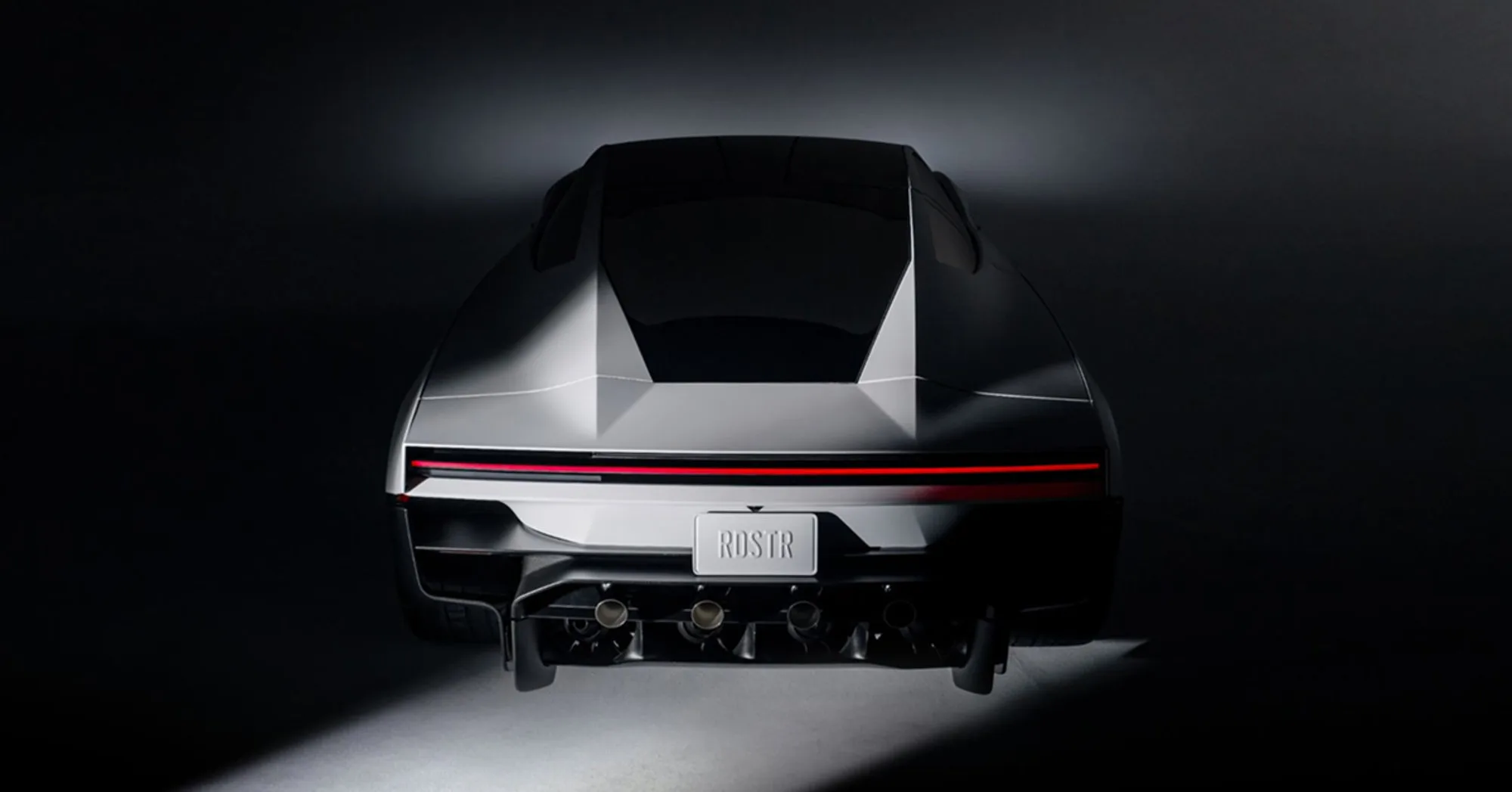 Rear studio view of the second-generation Tesla Roadster, with a full-width light bar and four round nozzles above the diffuser. The plate reads RDSTR.